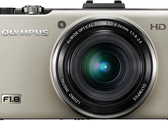 Silver Olympus digital camera with a large lens, labeled with F1.8 and HD on the front.