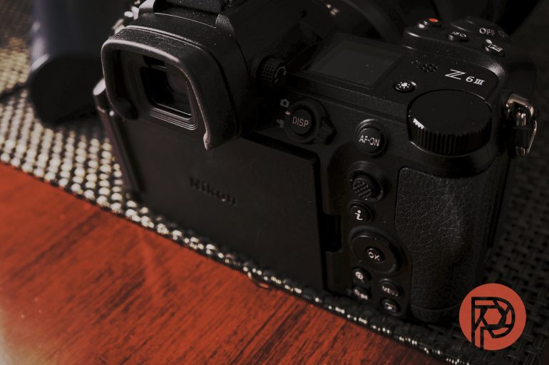Close-up of the back of a Nikon Z 6II camera on a woven mat, with a red circular logo in the corner.