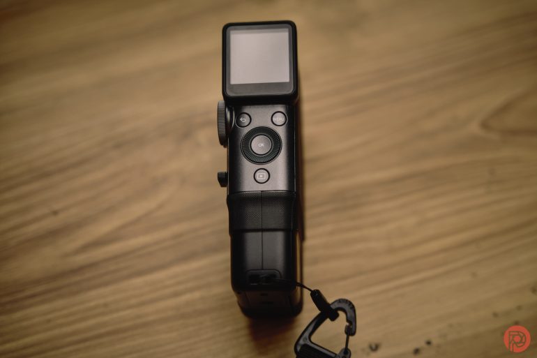 Black digital camera with a screen and buttons, placed on a wooden surface, viewed from above.