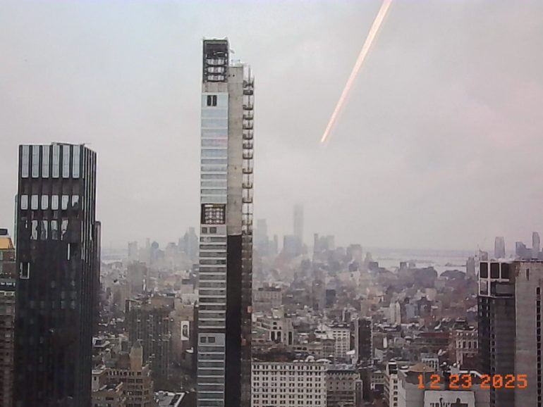 View of tall skyscrapers and city buildings on a cloudy day, with a date stamp 12 23 2025 in the corner.
