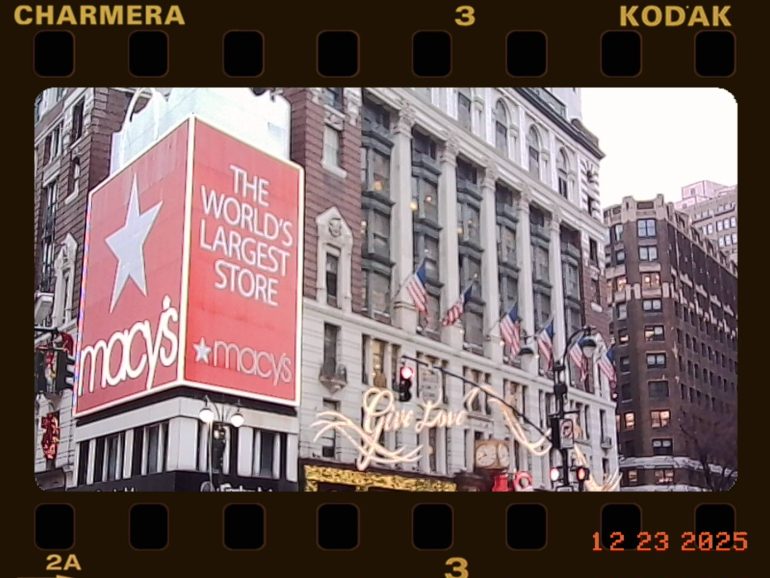 Macy’s Herald Square boasts The Worlds Largest Store sign, with American flags and holiday lights displayed.