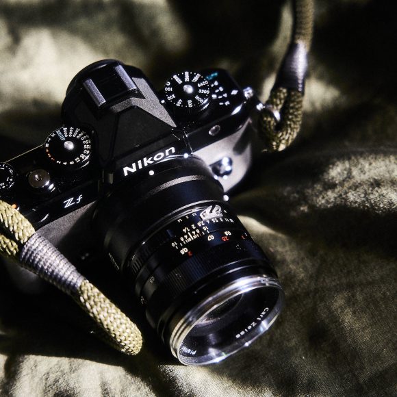 A Nikon Zf camera with a lens and strap lies on a textured green fabric.