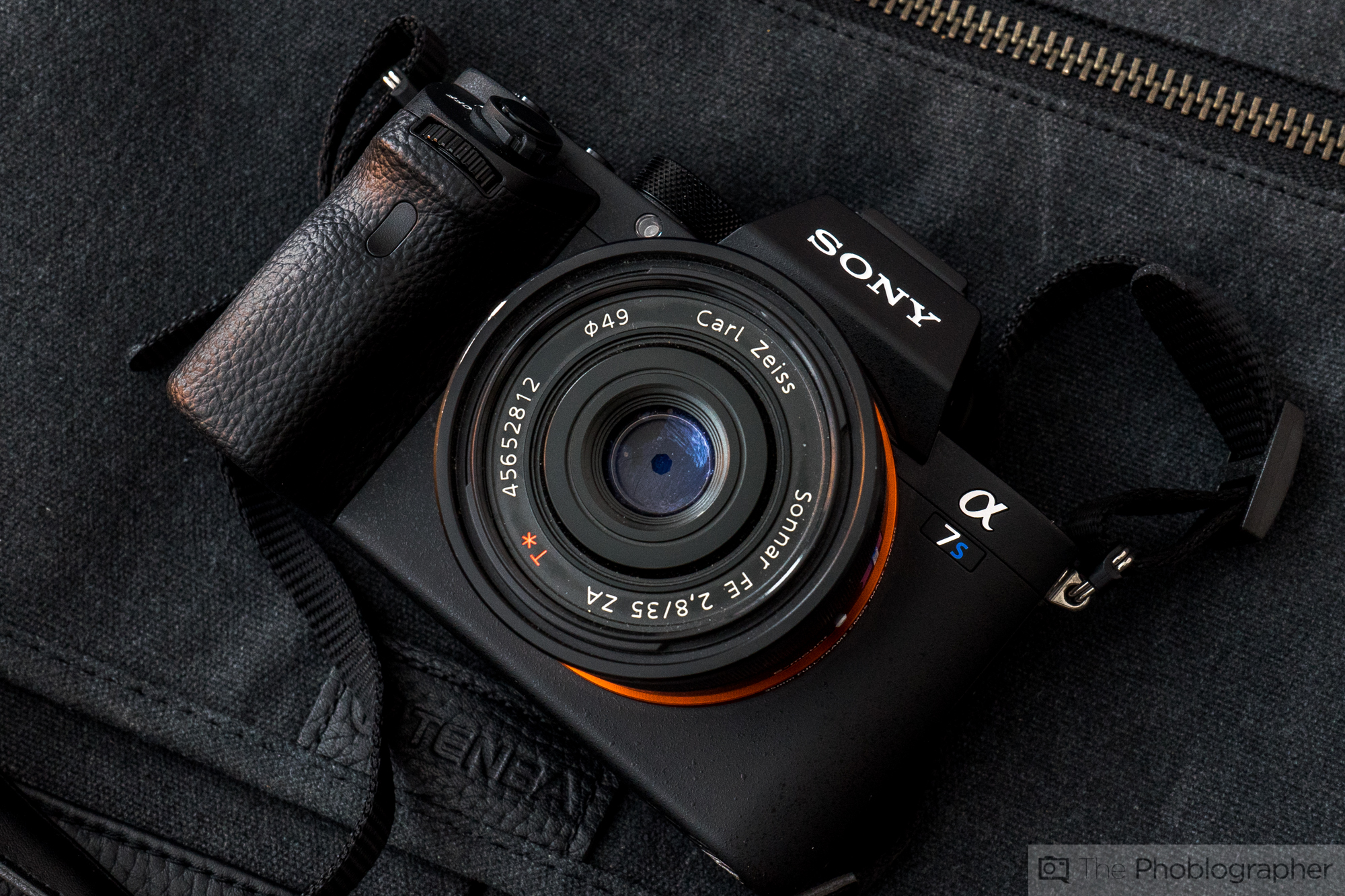 Sony α7S camera with a Carl Zeiss lens resting on a dark fabric background with a zipper.