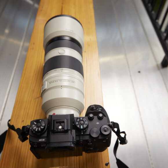 The Sony a9 III sits on top of a wooden bench.