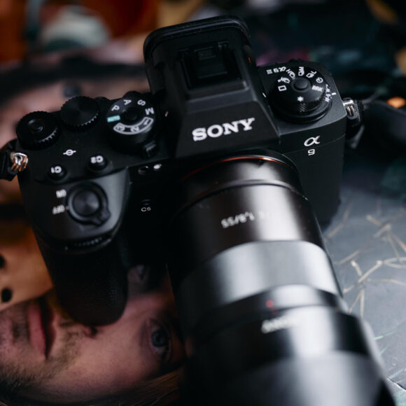 A Sony Alpha camera with a large lens rests on a magazine featuring a partial face and doll.