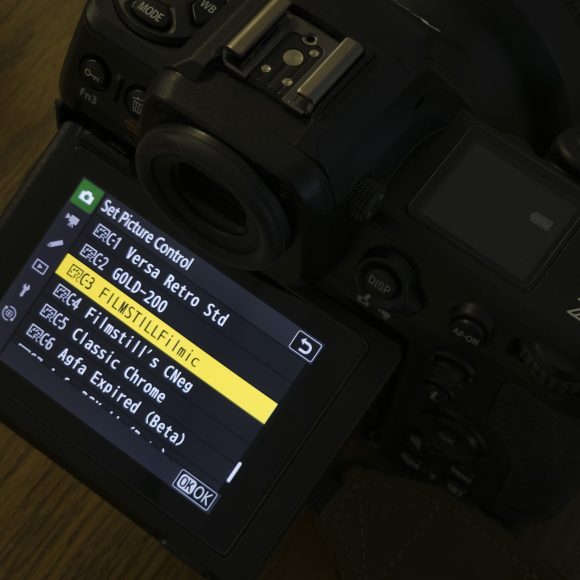 A camera screen displays a menu of film simulation presets, including FILMSTILL/Filmic and Classic Chrome.