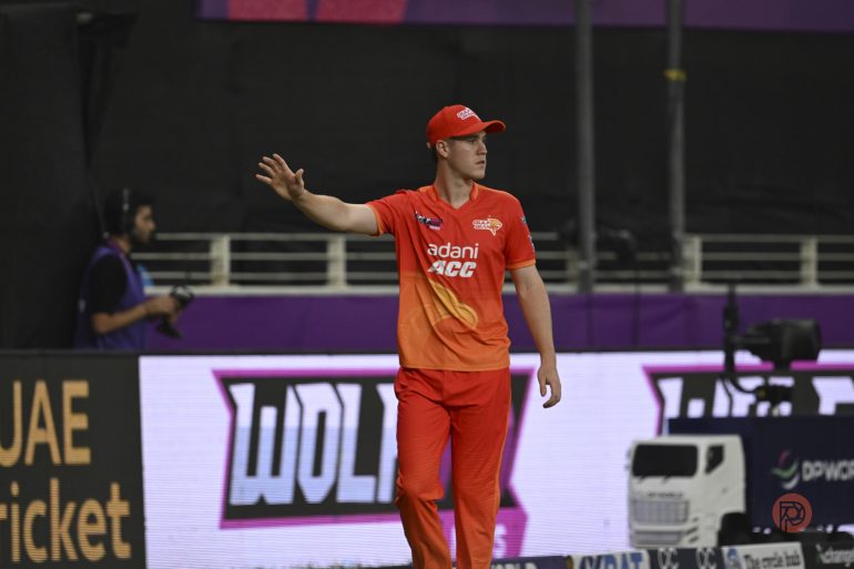 Cricket player in orange Sunrisers Hyderabad uniform gestures on field during a match.