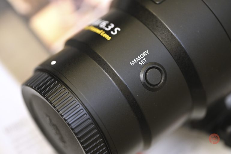 Close-up of a camera lens showing a black MEMORY SET button on its side.
