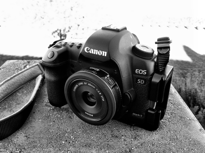 Black and white photo of a Canon EOS 5D Mark II camera on a ledge.