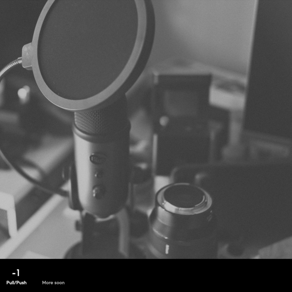 A close-up of a microphone and camera on a cluttered desk, shown in black and white.