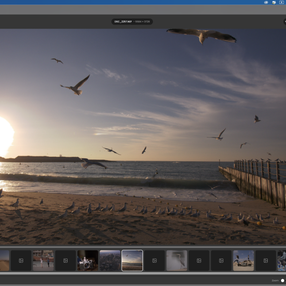 Photo editing software open showing a beach scene with flying seagulls, sunset, and a pier on the right.