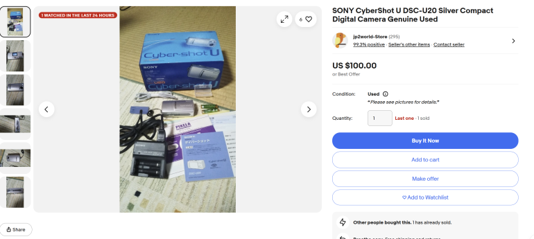 Sony CyberShot U camera with box, charger, cables, manuals, and accessories displayed on a table.